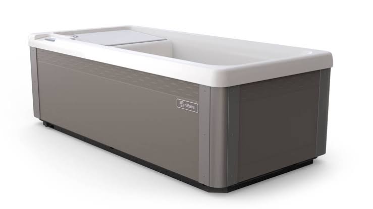A studio shot of the HotSpring cold plunge tub showing its modern exterior design with a grey textured cabinet, white top rim, and the official HotSpring logo on the side panel.