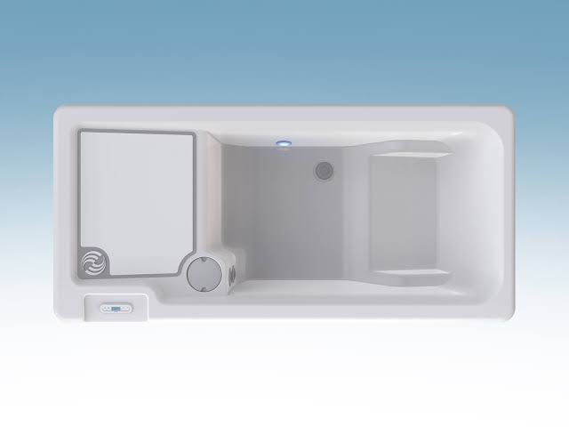 A top-down view of an empty, white HotSpring cold plunge tub showing its rectangular interior, built-in seating steps, and an integrated digital control panel on the top rim.