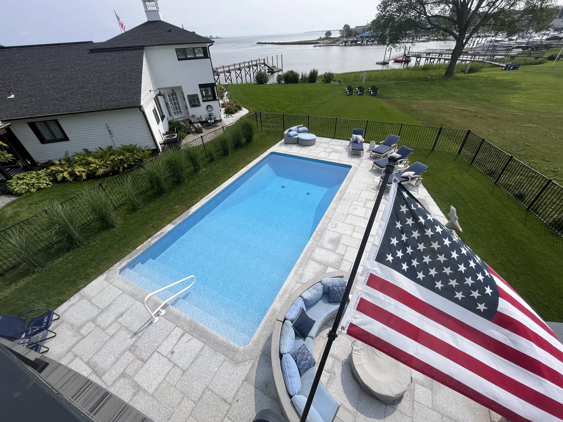 Elevated view of a rectangular in-ground pool with light-blue vinyl liner and paver deck at a waterfront property.